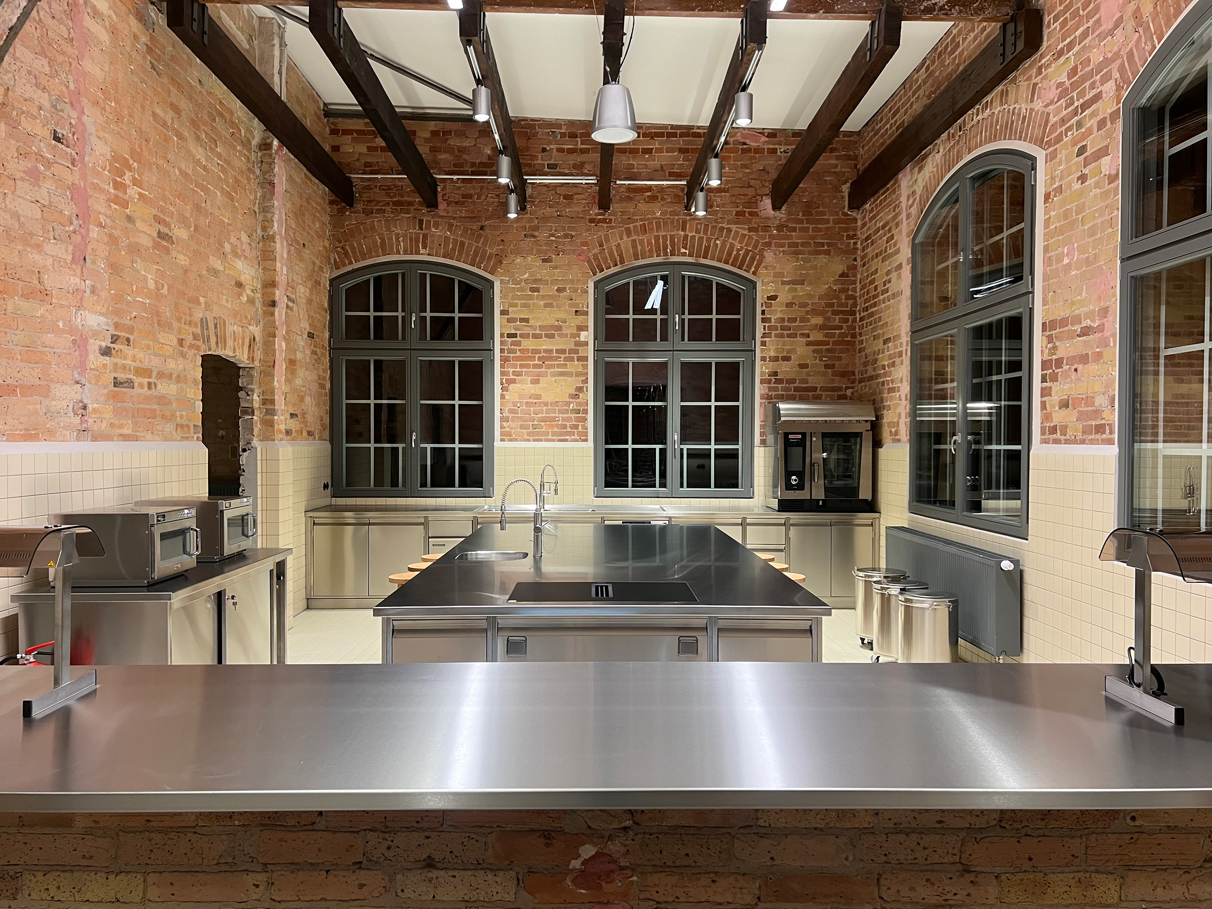 Edelstahl-Küche mit Meetingbereich in Raum mit Ziegelmauerwerk